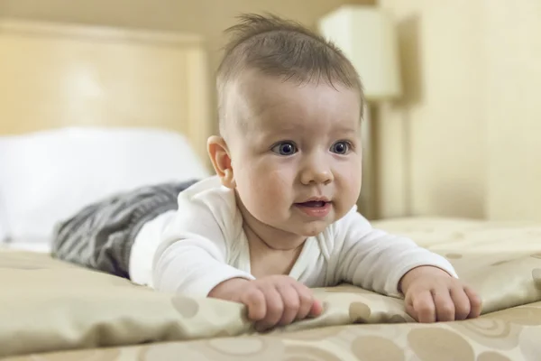 Menino brincando em uma cama — Fotografia de Stock