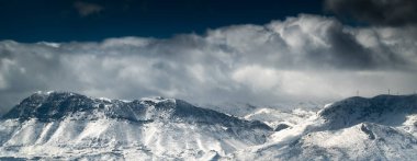 Beyaz bulutlarla kaplı görkemli karlı dağlar.