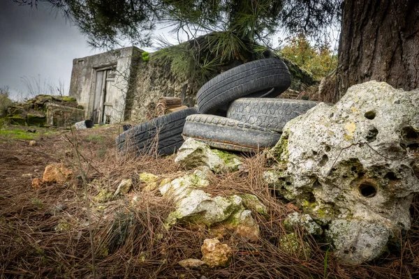 废弃的旧轮胎在树下的岩石旁边 — 图库照片