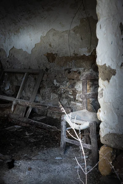 Abandoned old broken chair beside wall in house