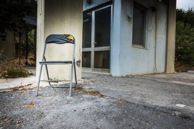 Sütunun yanındaki asfaltta kırık sandalye