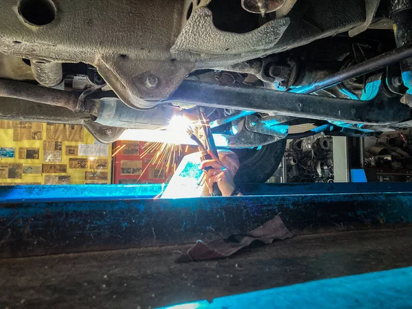 汽车修理厂机械工人用火花焊接金属排气管 — 图库照片