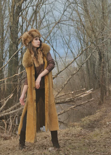 Moda belleza chica en abrigo de piel de pie en el fondo de la naturaleza a principios de primavera Fotos De Stock Sin Royalties Gratis