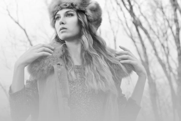 Girl in fur coat posing at branches background in black and white — 图库照片