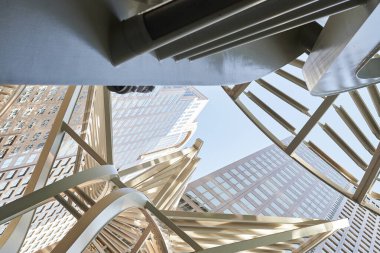 Warm tall peaked structures with metallic artistic geometric shapes in large leaf shapes in downtown calgary big clear blue cloudless sky on stairway