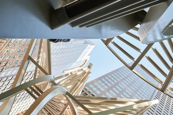 Warm tall peaked structures with metallic artistic geometric shapes in large leaf shapes in downtown calgary big clear blue cloudless sky on stairway
