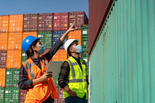 Team of logistic engineer man and woman with medical face mask standing outside on a large commercial dock during pandemic