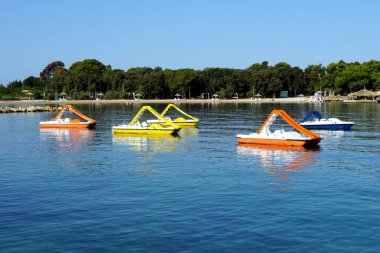 Novalja, Hırvatistan, 22 Ağustos 2021. Turistik Novalja kasabasındaki plajların önünde yüzen renkli pedallı botlar.