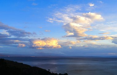 Karanlık kış günbatımında deniz yüzeyinde bulutlarla dramatik bir gökyüzü.