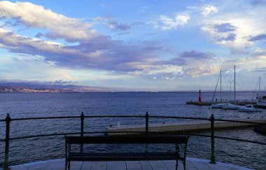 Kolej gününde açık denize bakan boş bir bank.