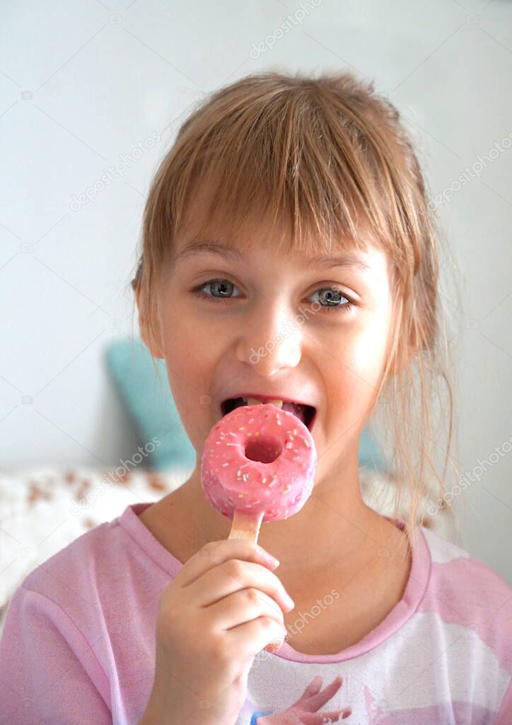 The cute ten years old girl with the pink ice cream in her mouth