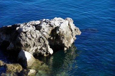 A large limestone rock in the sea and its reflection in the seawater