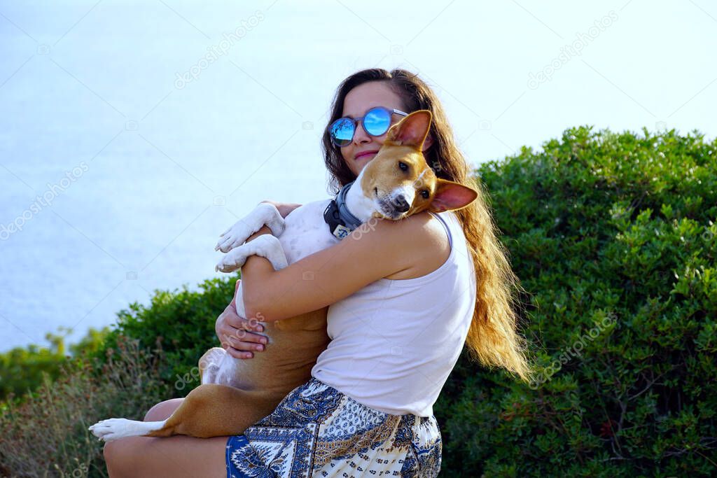 A beautiful young woman brunette and a pet dog she holds in her arms