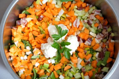 Maydanoz yaprağı, yemek pişirmeye hazır taze sebzelerle dolu bir tencerede beyaz karnabahar parçalarının süslenmesi için.