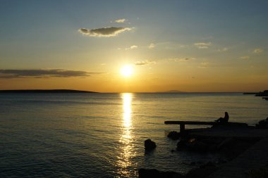 Deniz yüzeyinin üstündeki taş iskelenin silueti... sakin yaz günbatımında... gökyüzü manzaralı deniz manzarasında...