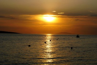 Turuncu renkte gün batımında denizin yüzeyindeki güneş ışınlarının yansıması.