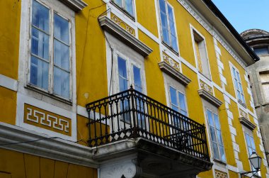 19. yüzyıldan kalma balkonu ve birçok penceresi olan terk edilmiş sarı bir binanın dış cephesi.