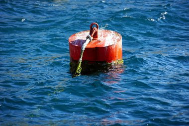 Mavi denizde yüzen gemi ve tekneler için kırmızı metal bir şamandıra.