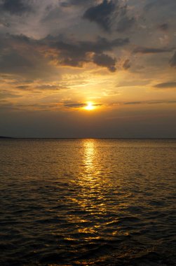 Beautiful sundown above golden and wavy sea surface in warm color tones
