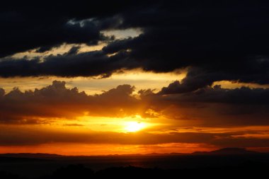 Black clouds in layers above seascape around a sun ball after strong summer storm