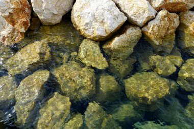 Big stones in shallow transparent turquoise sea water from up aerial view