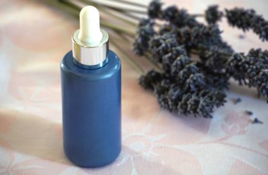 Kozmetik yağlar için mavi cam şişe. Arka planda bulanık bir damlası var.