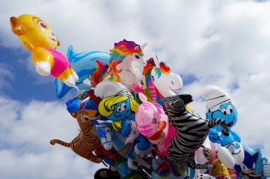 Gökyüzünde rüzgarda sallanan renkli helyum çocuk balonları.