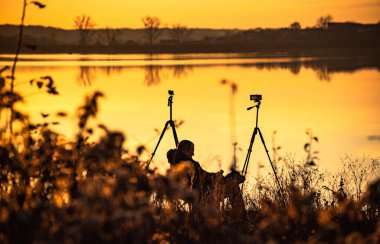 Akıllı telefon gölde günbatımı videosu çekiyor.