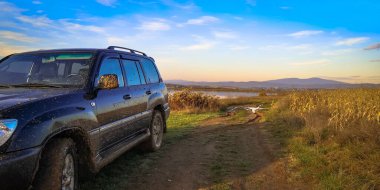 Gün batımında gölün yanında bir cip.