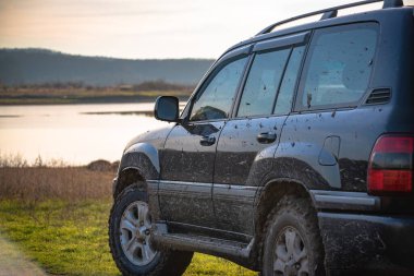 Gün batımında gölün yanında bir cip.