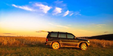 Gün batımında gölün yanında bir cip.