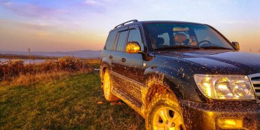 Gün batımında gölün yanında bir cip.