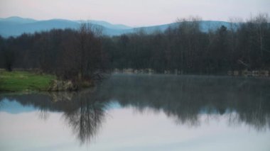 Kış günbatımı manzarası sisli bir dağ gölü üzerinde
