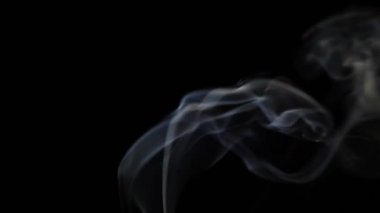 Beautiful movement of smoke in a beam of light on a dark background