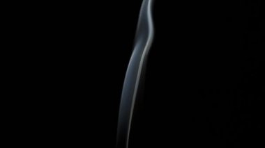 Beautiful movement of smoke in a beam of light on a dark background