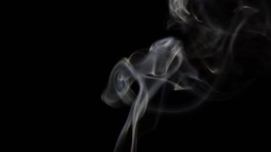 Beautiful movement of smoke in a beam of light on a dark background