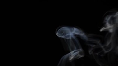 Beautiful movement of smoke in a beam of light on a dark background