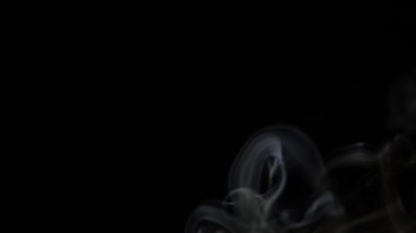Beautiful movement of smoke in a beam of light on a dark background