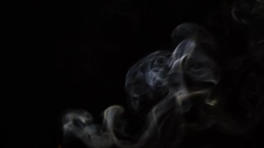 Beautiful movement of smoke in a beam of light on a dark background