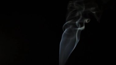 Beautiful movement of smoke in a beam of light on a dark background