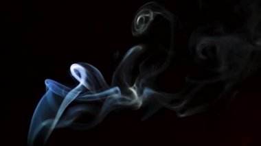 Beautiful movement of smoke in a beam of light on a dark background