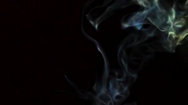 Beautiful movement of smoke in a beam of light on a dark background