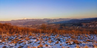 Kış günbatımında karla kaplı bir dağ manzarası