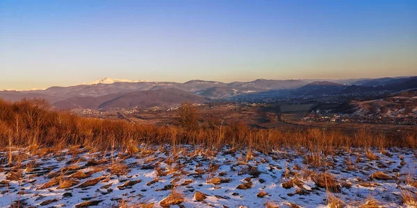 Kış günbatımında karla kaplı bir dağ manzarası