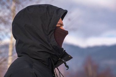 Kış giysileri içindeki genç adam dağların arka planında