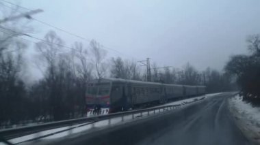 Banliyö treni yağmurdan gelen ıslak camlar arasında hareket ediyor