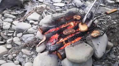 Bir dağ nehrinin kıyısında ateşte yemek pişirmek.