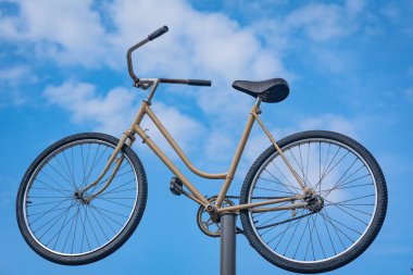 Mavi gökyüzüne karşı demir bir direkte eski bir bisiklet