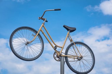 Mavi gökyüzüne karşı demir bir direkte eski bir bisiklet