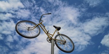 Mavi gökyüzüne karşı demir bir direkte eski bir bisiklet